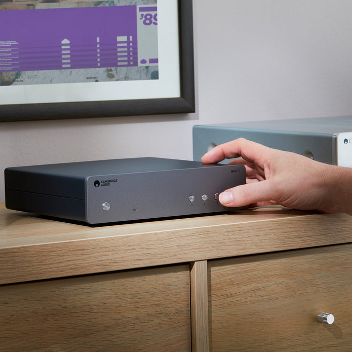 Lifestyle view of cambridge audio network player in living room with man turning it on