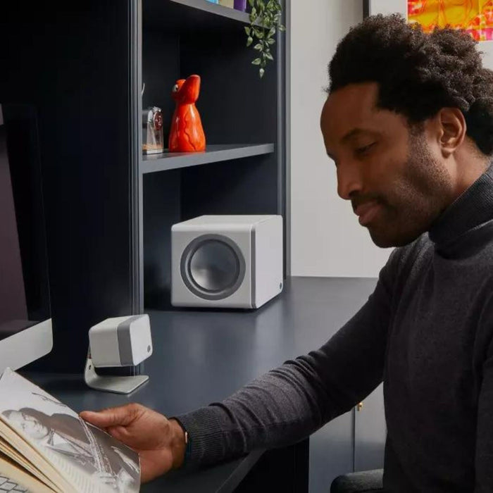 man listening to cambridge audio x201 subwoofer while he reads